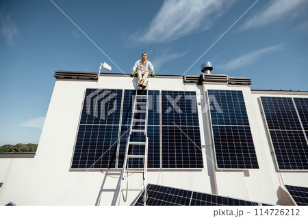 Man on rooftop of a private house with solar power station 114726212