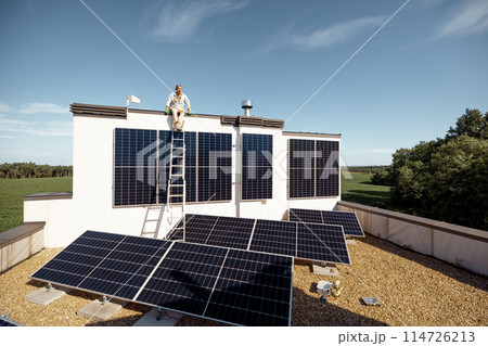 Man on rooftop of a private house with solar power station Man on rooftop of a private house with solar power station 114726213