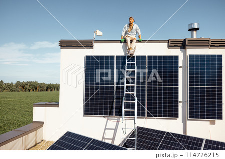Man on rooftop of a private house with solar power station 114726215