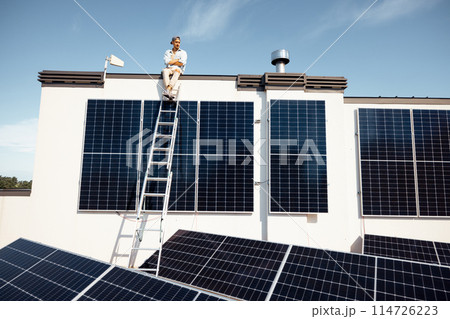 Man on rooftop of a private house with solar power station 114726223