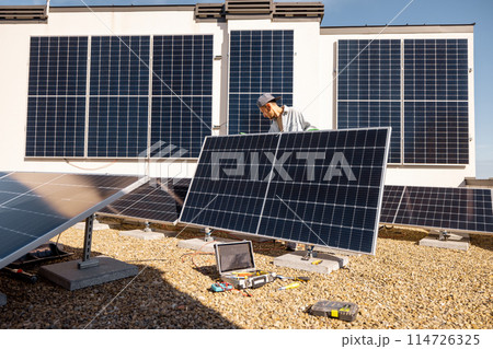 Man installing solar panels on the roof of his house Man installing solar panels on the roof of his house 114726325