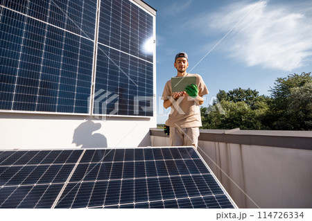 Technician with a digital tablet on a rooftop with solar power station 114726334