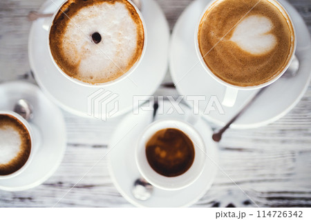 Cups with hot espresso, cappuccino, latte on table. 114726342
