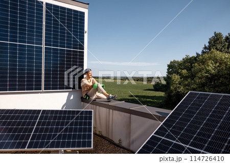 Man on a rooftop of his house with a solar power station Man on a rooftop of his house with a solar power station 114726410