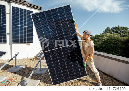 Man installing solar panels on a rooftop Man installing solar panels on a rooftop 114726493