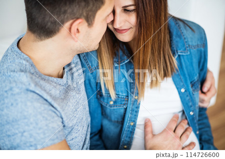 Pregnant woman and her partner, touching her belly. 114726600