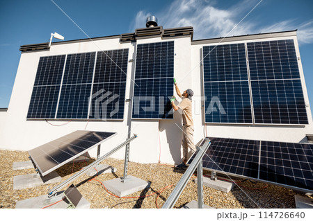 Man installing solar panels on a rooftop 114726640