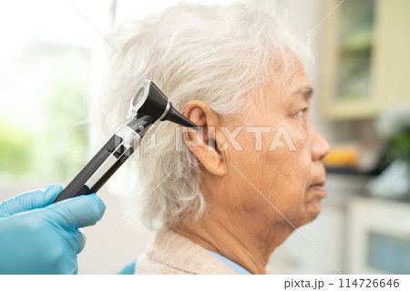 Audiologist or ENT doctor use otoscope checking ear of asian senior woman patient treating hearing loss problem. Audiologist or ENT doctor use otoscope checking ear of asian senior woman patient treating hearing loss problem. 114726646