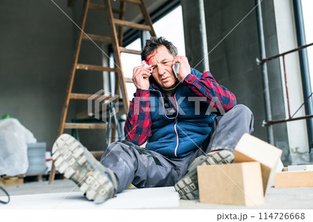 Injured worker with wound on head, head injury. Work injury, accident in workplace. 114726668