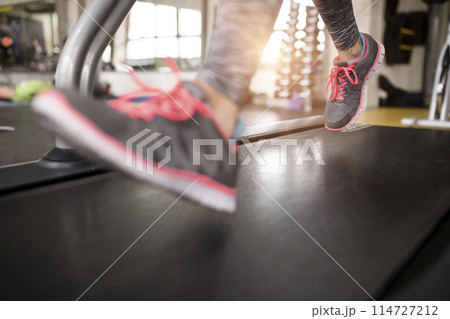 Closeup of feet in gym, running on treadmill. Routine workout for woman's physical and mental health. Closeup of feet in gym, running on treadmill. Routine workout for woman's physical and mental health. 114727212