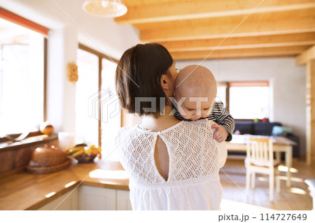 Mother holding small baby, carrying him around house. Unconditional paternal love, mother's Day concept. 114727649