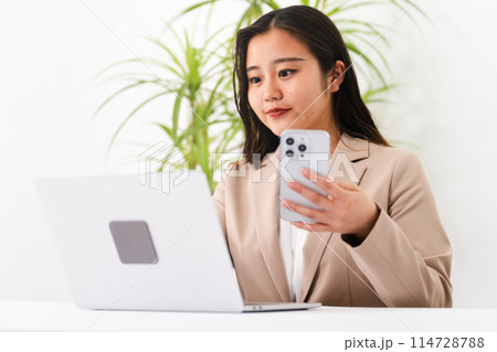 ビジネススーツを着てラップトップを操作している若い女性　ビジネスイメージ	 114728788
