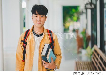 Happy smiling student with book in hand on campus while going to study for learning. Happy smiling student with book in hand on campus while going to study for learning. 114729259