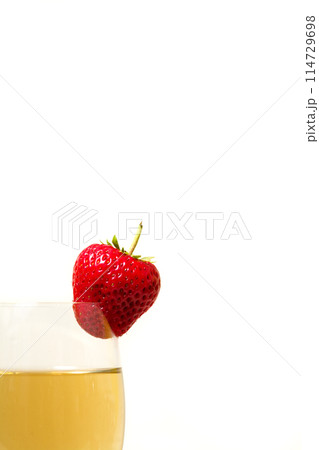 Red and ripe strawberry on glass with a yellow drink Red and ripe strawberry on glass with a yellow drink 114729698