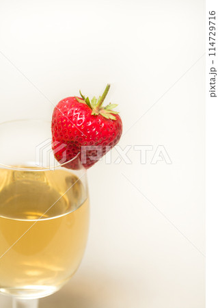 Red and ripe strawberry on glass with a yellow drink 114729716