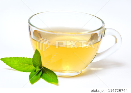 Glass transparent cup with tea and green mint leaf Glass transparent cup with tea and green mint leaf 114729744