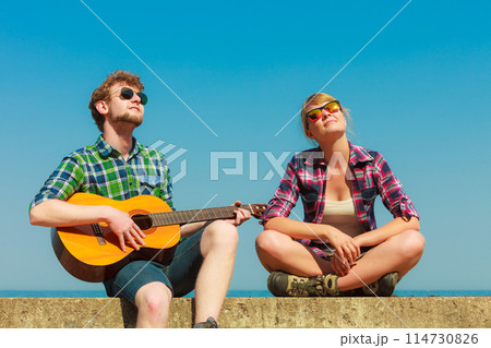 Young man playing guitar to his girlfriend outdoor Young man playing guitar to his girlfriend outdoor 114730826