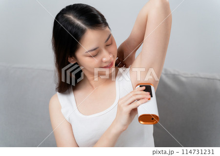 A beautiful woman is epilating her armpits using an IPL laser hair removal epilator device. A beautiful woman is epilating her armpits using an IPL laser hair removal epilator device. 114731231