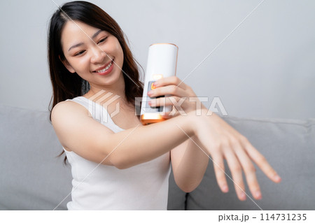 A beautiful woman is epilating and removing hair using an IPL laser hair removal epilator device. A beautiful woman is epilating and removing hair using an IPL laser hair removal epilator device. 114731235