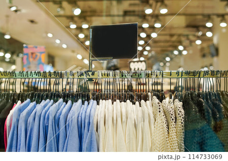 Clothes on hangers with black sign for text in a retail shop . Fashion and shopping center 114733069