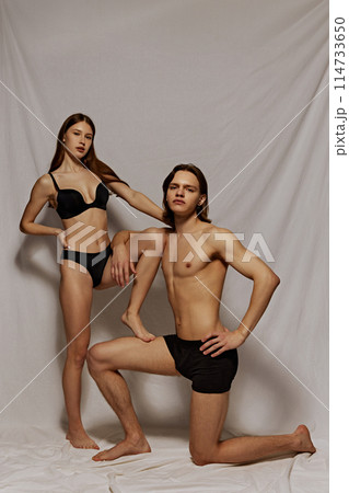 Young beautiful people, man and woman with healthy, fit, perfect body shape posing in black underwear against grey textile background 114733650