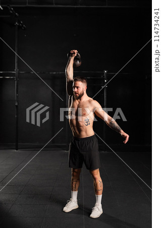 Man lifting a weight with hand, one arm dumbbell snatch, bare chest. Routine workout for physical and mental health. 114734241