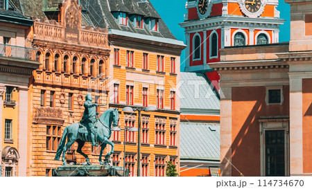 A statue of a man riding a horse in front of a clock tower in a city A statue of a man riding a horse in front of a clock tower in a city 114734670