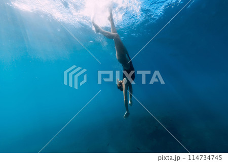 Woman dive to the sea bottom in blue ocean. Free diving with beautiful girl in ocean 114734745