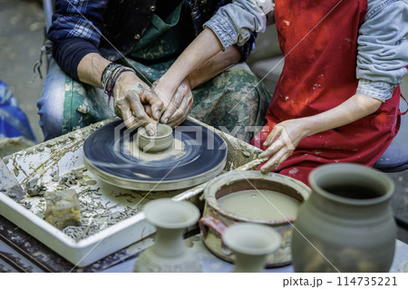 Man and a child are making pottery. The man is teaching the child how to make pot Man and a child are making pottery. The man is teaching the child how to make pot 114735221