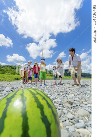 川原でスイカ割りをする家族連れ 114736498