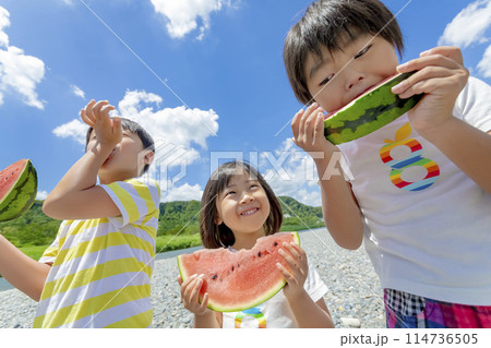 川原でスイカを食べる子供たち 114736505