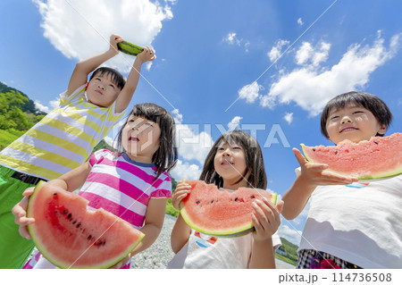 川原でスイカを食べる子供たち 114736508