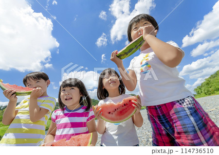 川原でスイカを食べる子供たち 114736510