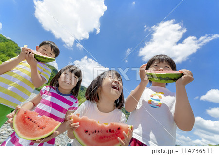 川原でスイカを食べる子供たち 114736511