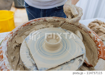 Creating clay dishes on potter wheel, a potter hand sculpts soft clay with wet hands 114737115
