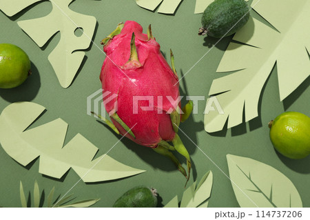 Tropical fruit and paper tropical leaves on green background, top view Tropical fruit and paper tropical leaves on green background, top view 114737206