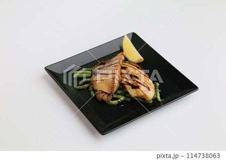 Baked white fish tilapia fish fillet on black plate isolated on white background Baked white fish tilapia fish fillet on black plate isolated on white background 114738063