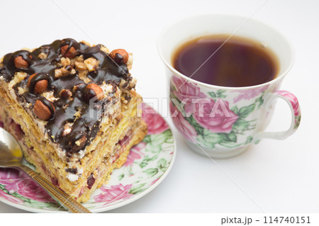 Piece of cake with hazelnuts, teaspoon and cup 114740151