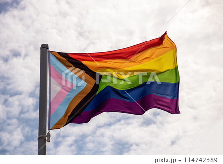 Pride Flag Fluttering in the Breeze Against a Cloudy Summer Sky Pride Flag Fluttering in the Breeze Against a Cloudy Summer Sky 114742389