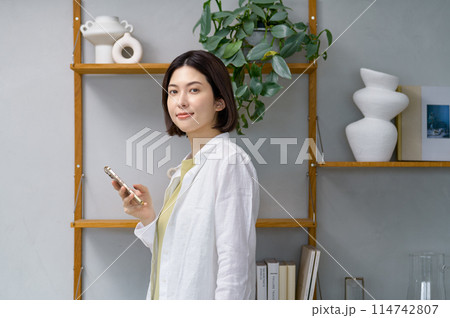 部屋でスマホを見る若い女性 114742807