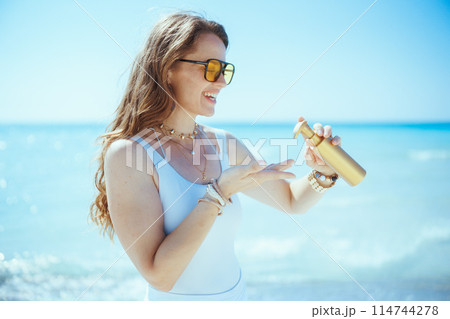 smiling stylish 40 years old woman on seashore with spf 114744278