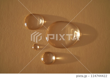 Beautiful volumetric drops of cosmetic product on a beige background. Beautiful volumetric drops of cosmetic product on a beige background. 114744422