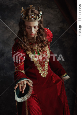 medieval queen in red dress with crown making reverence 114744590
