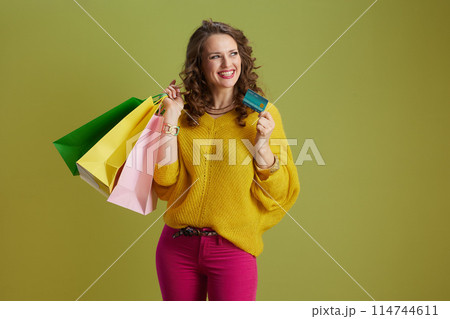 happy fit woman in yellow sweater isolated on green 114744611