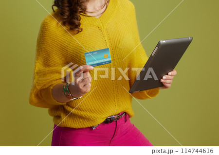 Closeup on fit female using digital tablet on green background 114744616