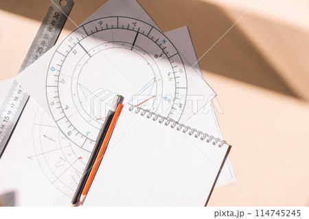 Natal chart on white paper with pencils and ruler on an orange background Natal chart on white paper with pencils and ruler on an orange background 114745245