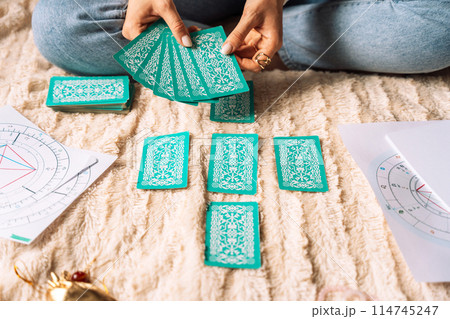 Lady laying out tarot cards with green cover while sitting on bed Lady laying out tarot cards with green cover while sitting on bed 114745247