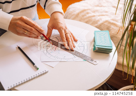 Lady draws with a pencil and ruler on a natal chart 114745258