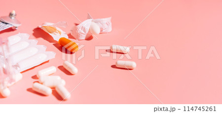 Rectal candles in packaging and unpacked and ointment in a tube on a pink background 114745261