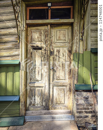 Old building wooden door with textured surface, a hole for mail and a round handle 114746001